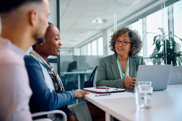 Happy business woman talking to young couple during a meeting in the office